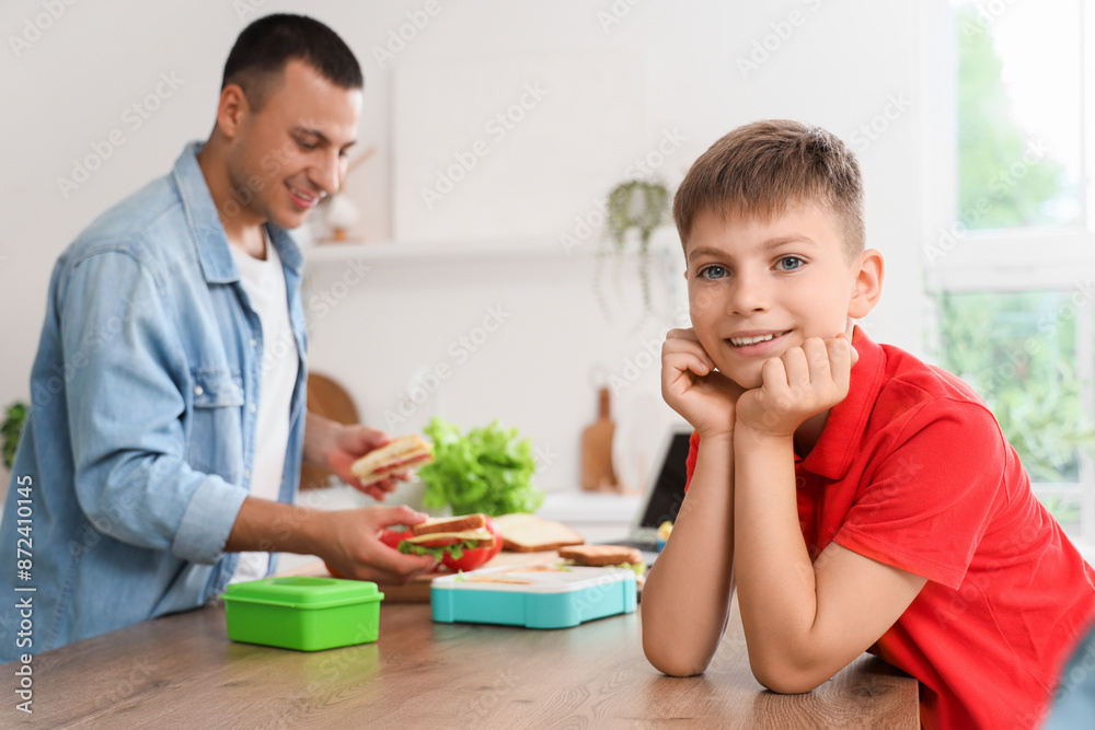 Little boy with his father packing school lunchbox in kitchen Little boy with his father packing school lunchbox in kitchen