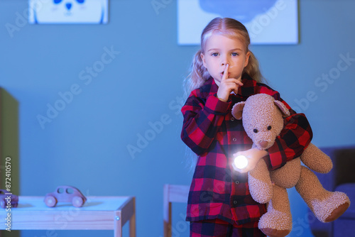 Little girl in pajamas hold...