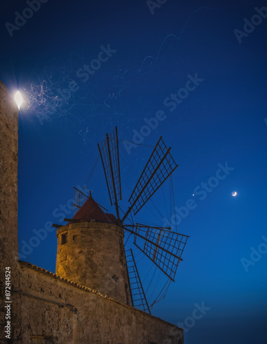 Salt mine and windmill in Trapani at cloudless night. June 2023 photo