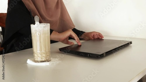 A woman who was sitting then opened and turned on the laptop on the table