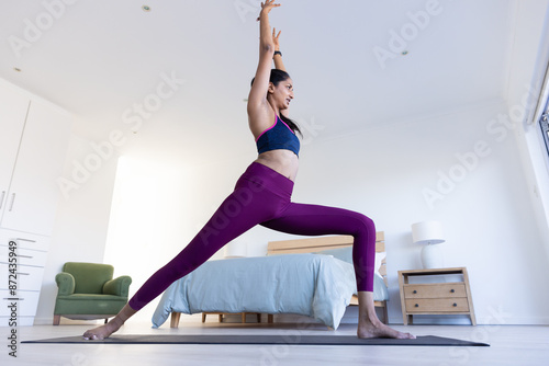 Practicing yoga, woman stretching on yoga mat in bedroom for fitness