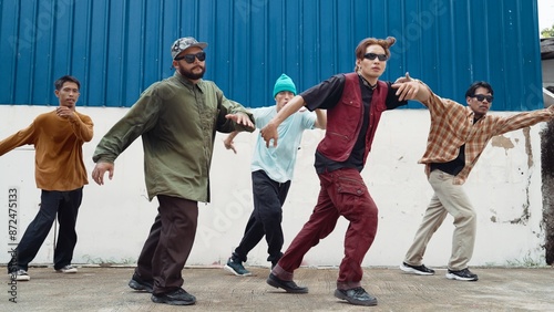 Group of hip hop choreographer dancing street dance together at wall. Young break dancer practicing break dance, moving to modern rhythm, express feeling of lively. Outdoor 2024. Hiphop.