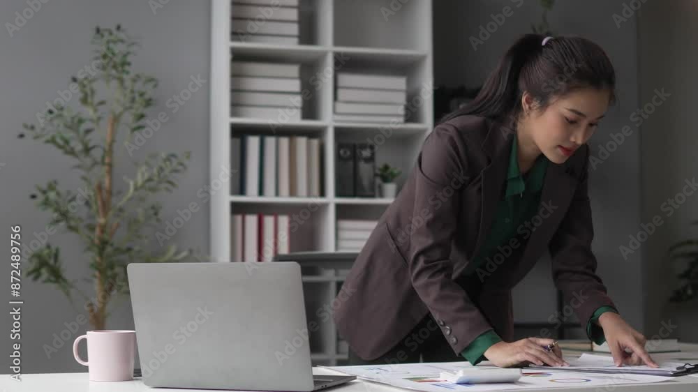 Young businesswoman analyzing documents in a modern office space, focusing on productivity and strategic planning Young businesswoman analyzing documents in a modern office space, focusing on productivity and strategic planning