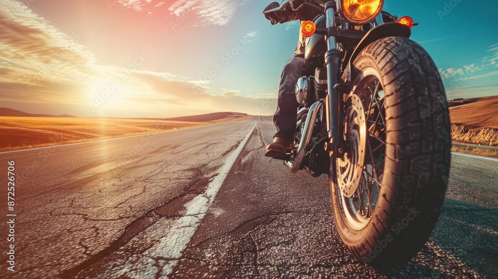 Naklejka premium Close-up shot of a motorbike rider on the road with empty space around him and a background of desert and blue sky. Capturing the thrill of the ride in an open, expansive landscape