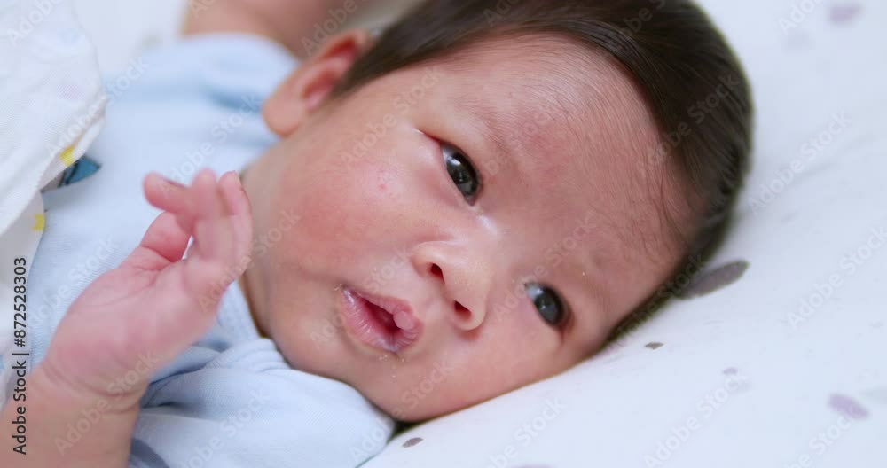 A small newborn baby is cooing and stretching as it looks at things and people that are around in the room. A small newborn baby is cooing and stretching as it looks at things and people that are around in the room.