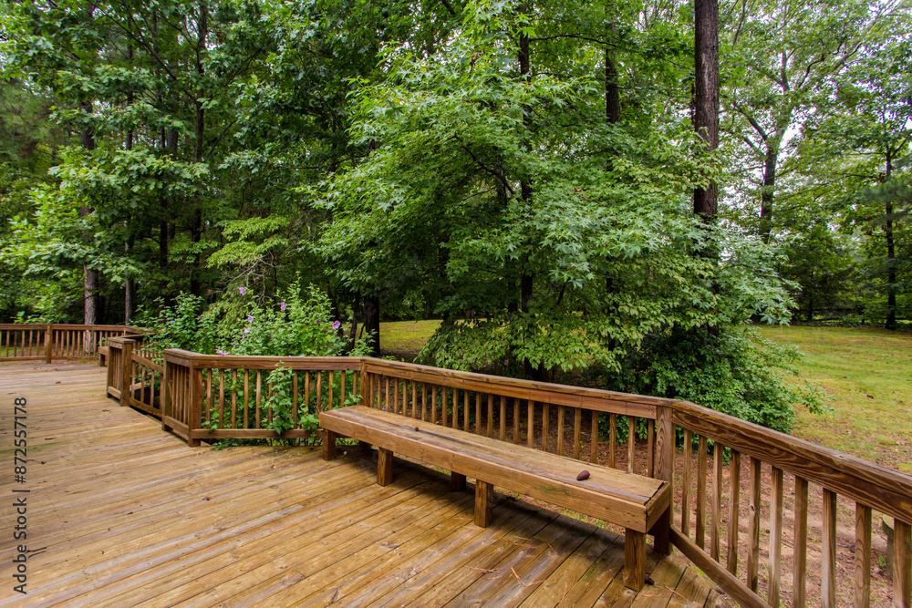 Expansive Wooden Deck With Built-In Bench And Lush Green Surroundings