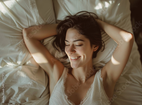 A photo of a woman waking up happy, stretching in bed with her hands behind her head and smiling, morning light, warm tones