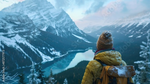An elated traveler gazes out at a snowy mountain lake from a scenic viewpoint, their face illuminated by the soft light of dawn, their joy evident as they soak in the breathtaking vista, with