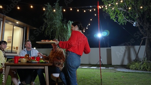 Family celebrate holiday in garden, Grandmother serve food for family member. Outdoor camping activity to relax with tasty meal and spend time with young generation cross generation gap. Divergence. photo