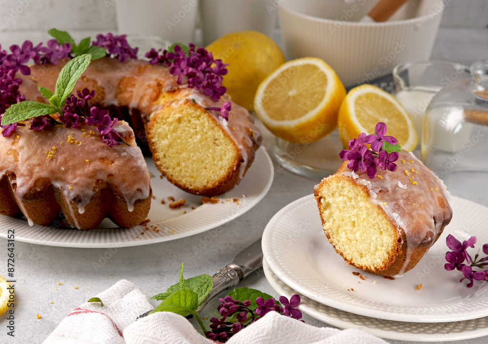 Still life of lemon cake with slice and with lilac on white table Still life of lemon cake with slice and with lilac on white table