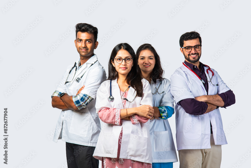 Group portrait of four indian asian young doctors in uniform standing against white background Group portrait of four indian asian young doctors in uniform standing against white background