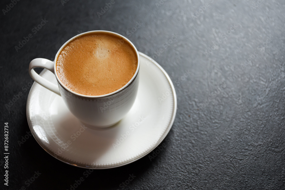 Top view of hot espresso coffee or Americano in a white glass cup on a black background 2024. Beautiful white cup of black coffee on the black table. Top view of hot espresso coffee or Americano in a white glass cup on a black background 2024. Beautiful white cup of black coffee on the black table.