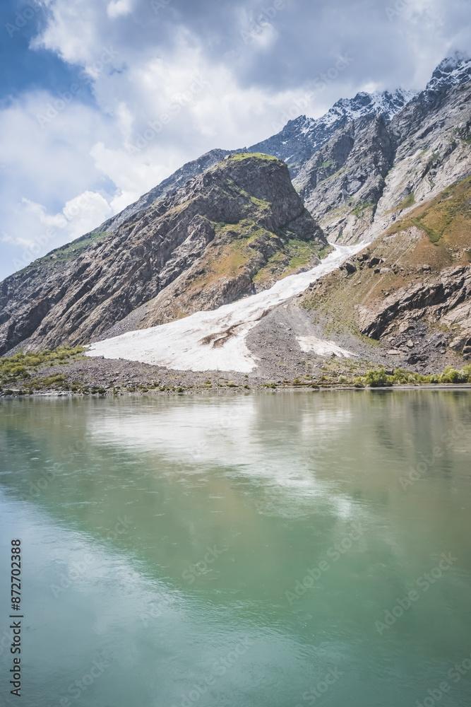 Obraz premium Blue mirror water of Panj river between Afghanistan and Tajikistan, river flows in a valley among rocky mountains in the Pamirs, panoramic landscape for background