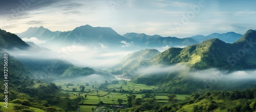 Fototapeta Naklejka Na Ścianę i Meble -  Mountain landscape filled with mist in the morning offers a warm greeting to travelers with a foggy and cloudy tropical backdrop, featuring copy space image.