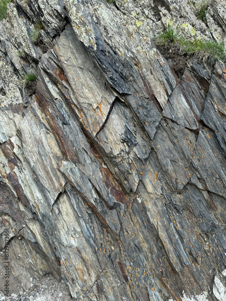 Photo of a fragment of gray and brown layered rock with pieces of moss in Kazbegi, Georgia Photo of a fragment of gray and brown layered rock with pieces of moss in Kazbegi, Georgia