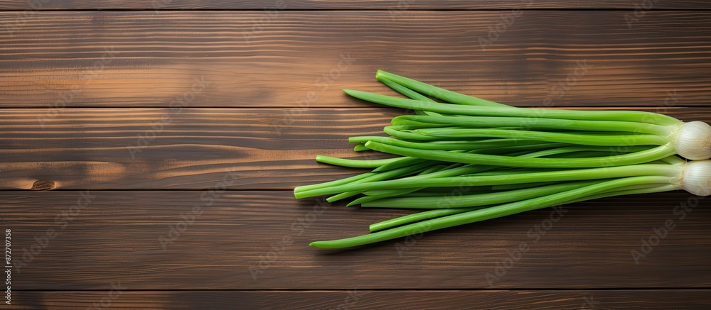 Top-down view of vibrant green onion placed on a wooden table with space for a photo. with copy space image. Place for adding text or design Top-down view of vibrant green onion placed on a wooden table with space for a photo. with copy space image. Place for adding text or design