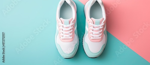 A pair of new sneakers set on a soft pink and blue pastel background with ample space alongside for additional imagery. Shot from above, showing a stylish perspective of the running shoes. © vxnaghiyev