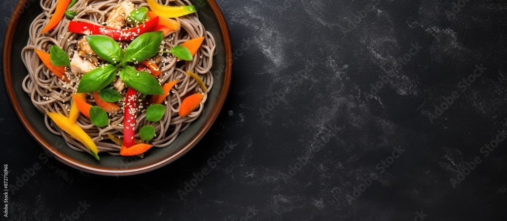 Top-down view of a grey bowl containing Japanese buckwheat soba noodles with chicken, carrots, bell pepper, and green beans, suitable for adding a copy space image. Top-down view of a grey bowl containing Japanese buckwheat soba noodles with chicken, carrots, bell pepper, and green beans, suitable for adding a copy space image.