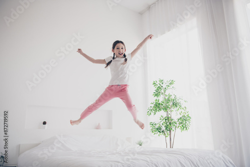 Full body portrait of adorable small girl jump rejoice wear pajama comfy bed bedroom apartment indoors