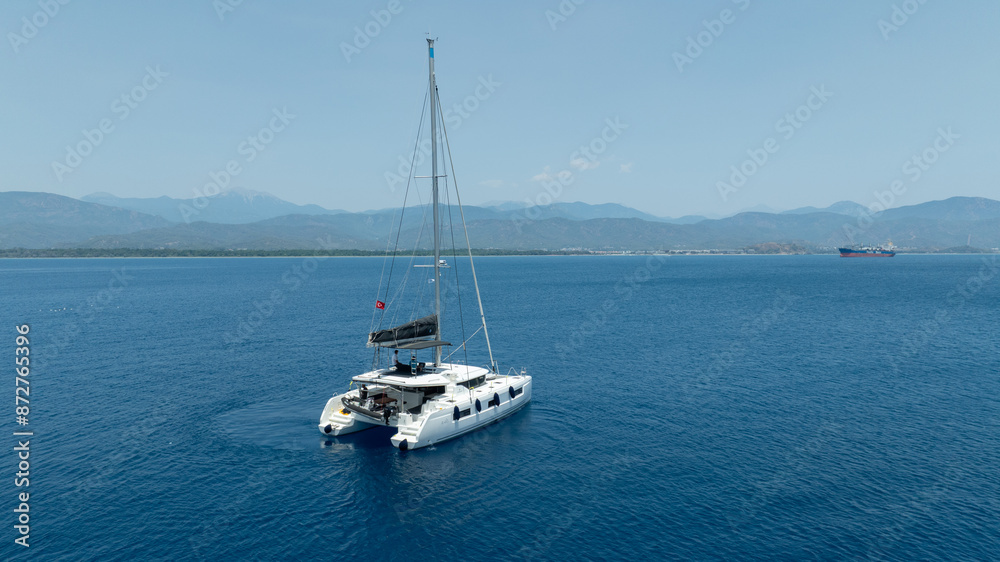 Aerial drone photo of beautiful catamaran sailing yacht anchored in tropical exotic turquoise sea exotic bay Aerial drone photo of beautiful catamaran sailing yacht anchored in tropical exotic turquoise sea exotic bay