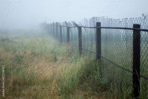 A chain-link fence going into the foggy distance