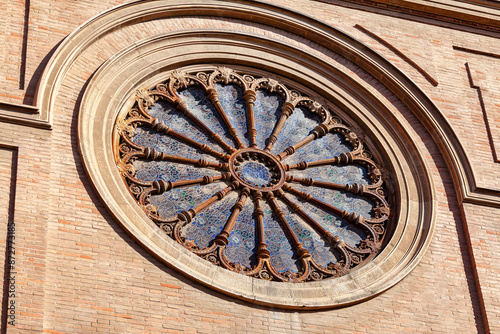 Stained glass window with a blue circle in the center. The window is on a cathedral with a brick exterior