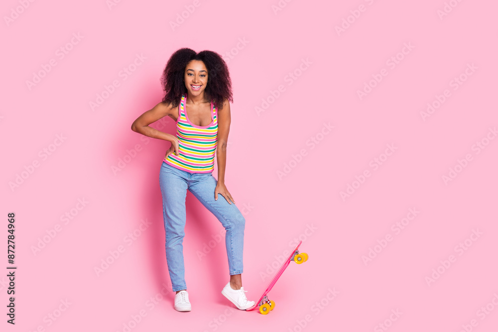 Full length photo of positive cheerful girl wear colorful top jeans stand with skateboard in summer isolated on pink color background Full length photo of positive cheerful girl wear colorful top jeans stand with skateboard in summer isolated on pink color background