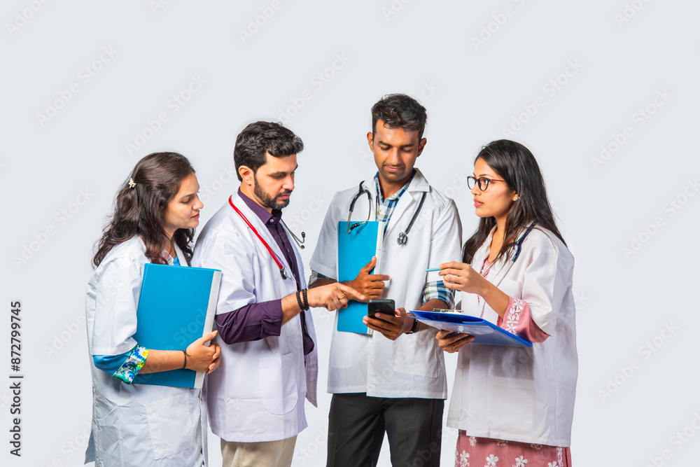 Group of Indian young medical practitiner or doctors using smartphone against white background Group of Indian young medical practitiner or doctors using smartphone against white background