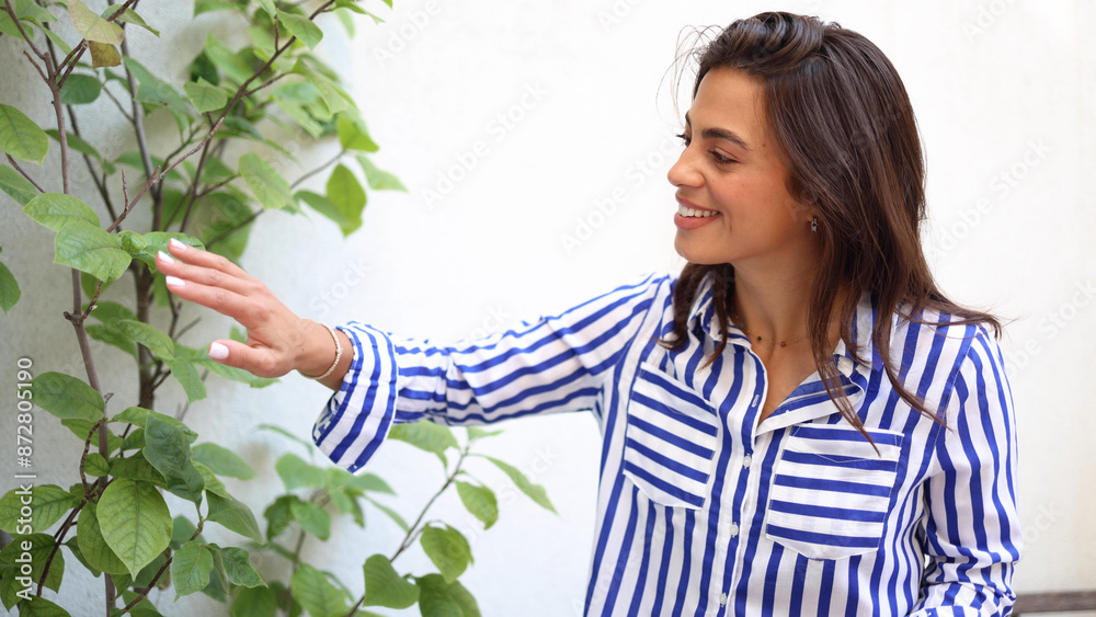 Beautiful, young woman taking care of her houseplants and enjoying Beautiful, young woman taking care of her houseplants and enjoying