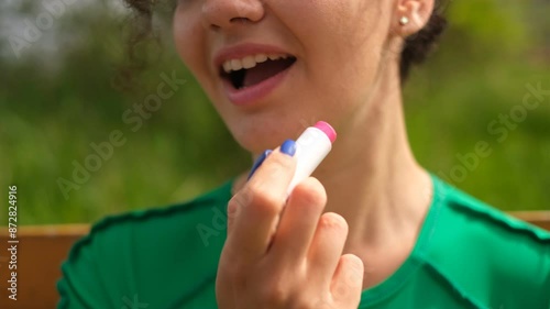 Woman applying lipstick to her lips close-up of her mouth
