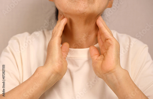 Elderly woman touching her neck with sore throat photo