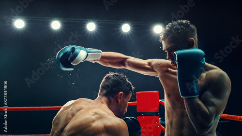Slika na platnu Two Male Boxers in an Electrifying Match, One Delivering Powerful Punch Under Bright Lights