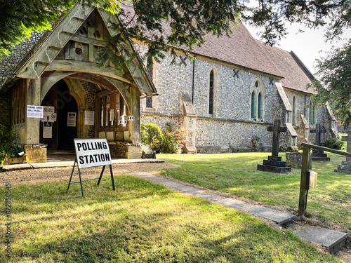 Polling station sign to show where to vote in an election outside a rural country church with graveyard