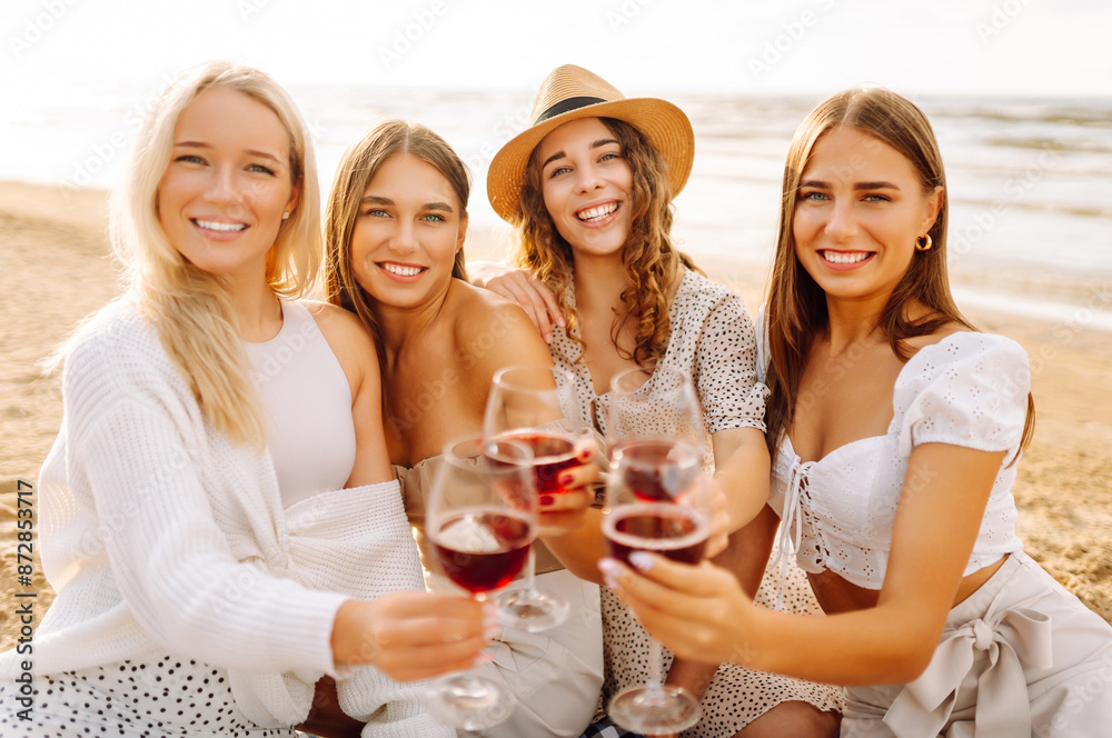 The company of gorgeous female friends having fun, cheers and drink wine, and enjoy picnic on the beach. Hen party. The company of gorgeous female friends having fun, cheers and drink wine, and enjoy picnic on the beach. Hen party.