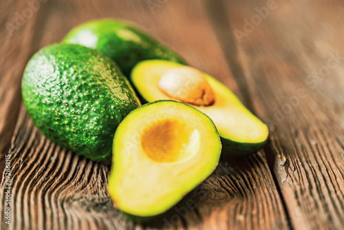 Fruits avocados cut and whole on a wooden background.
