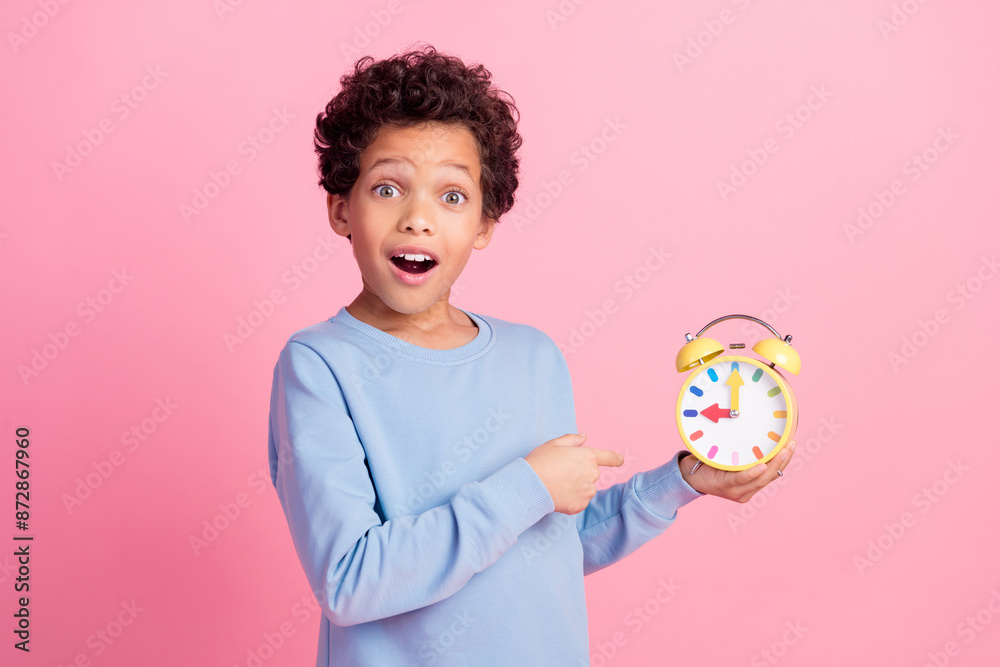 Photo of attractive funny grandson wear blue pullover pointing clock emtpy space isolated pink color background Photo of attractive funny grandson wear blue pullover pointing clock emtpy space isolated pink color background