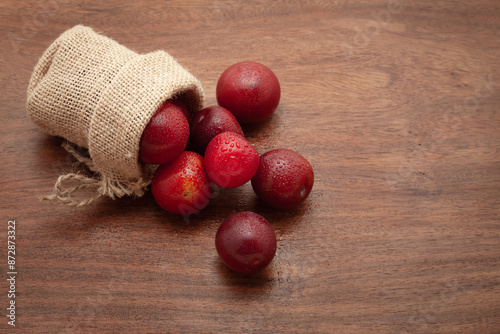 Top view of fresh Cherry Plum (Prunus cerasifera) fruits spilled out from a jute bag, on a wooden background. photo