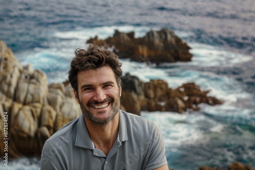 Portrait of a joyful caucasian man in his 30s wearing a sporty polo shirt isolated in rocky shoreline background