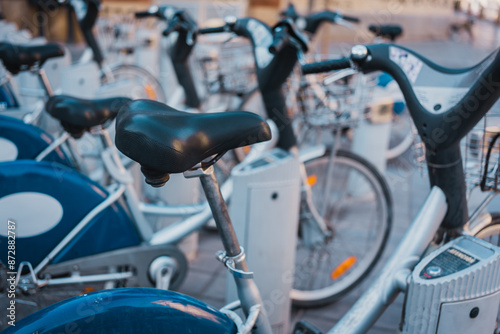Row of bicycles parked at a public bike-sharing station in an urban area. The bicycles are neatly arranged and ready for use, emphasizing sustainable transportation and city infrastructure.