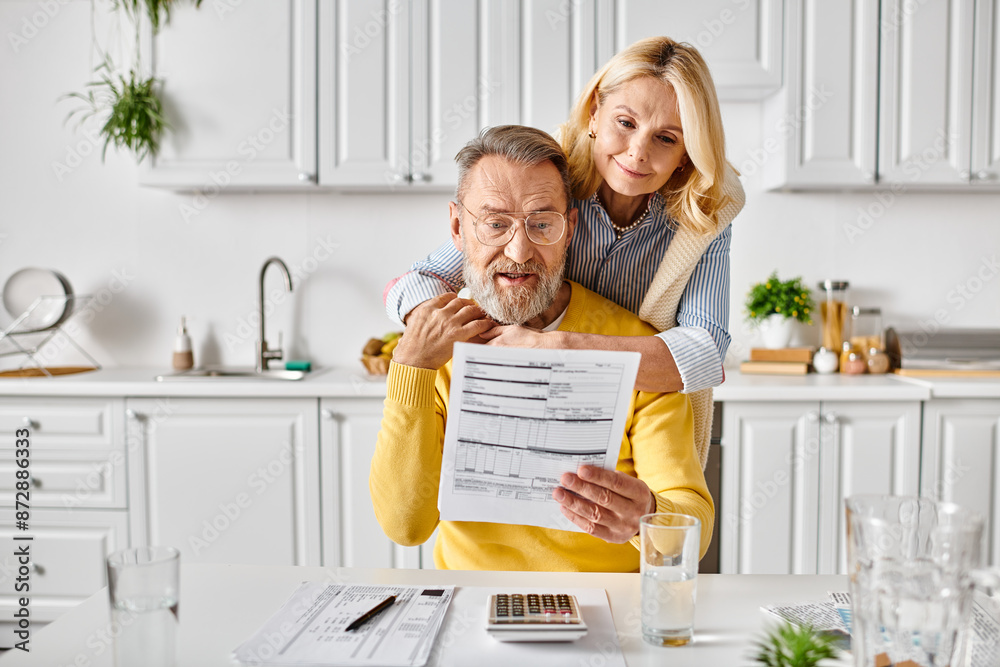 A man tenderly holds a woman above a table in a cozy kitchen, a scene of affection and closeness between a mature couple. A man tenderly holds a woman above a table in a cozy kitchen, a scene of affection and closeness between a mature couple.