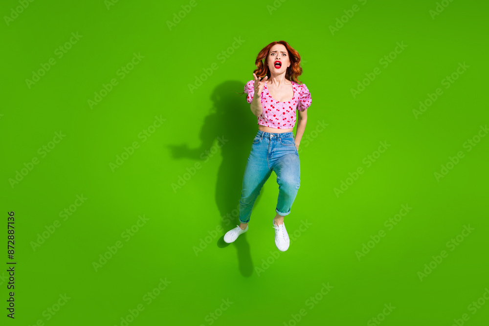 Full length photo of upset nervous lady dressed print top jumping high running empty space isolated green color background Full length photo of upset nervous lady dressed print top jumping high running empty space isolated green color background
