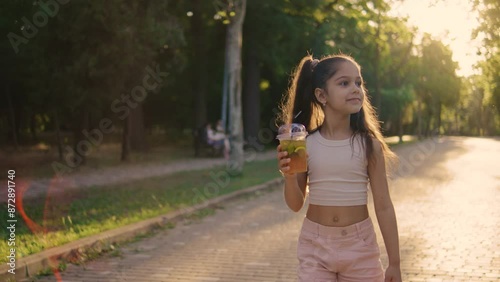 Wallpaper Mural A lovely young girl is happily sipping a beverage as she strolls along a sundrenched park trail Torontodigital.ca