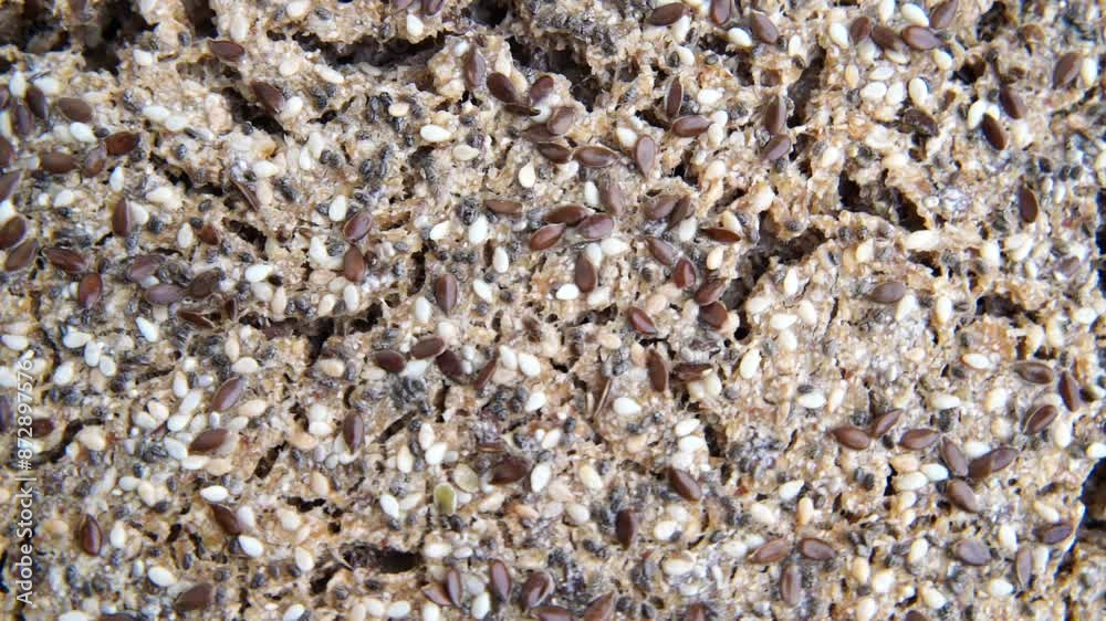 A close up of a piece of bread with a lot of seeds on it. The bread is brown and has a lot of texture. A close up of a piece of bread with a lot of seeds on it. The bread is brown and has a lot of texture.