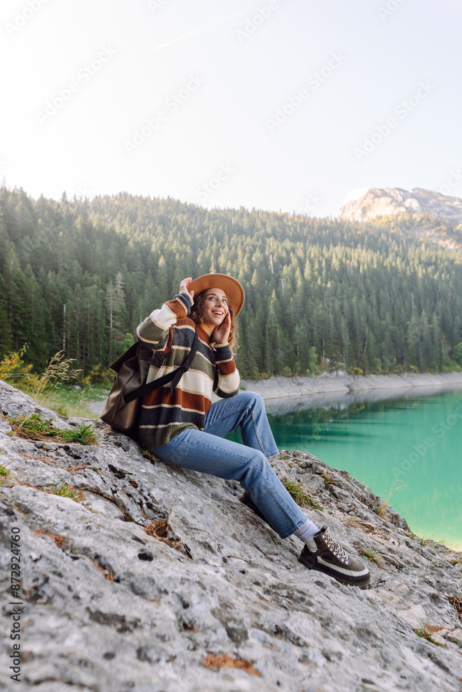 Naklejka premium Female traveler enjoying the view of Lake among mountains. Eco tourism. Active lifestyle.