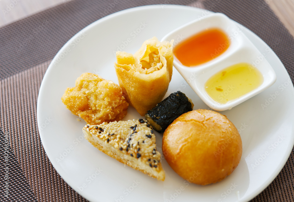Close up small portion of crispy Dim Sum on a white dish with natural light, baked and deep fried Dim Sum with two types of sauce. Close up small portion of crispy Dim Sum on a white dish with natural light, baked and deep fried Dim Sum with two types of sauce.