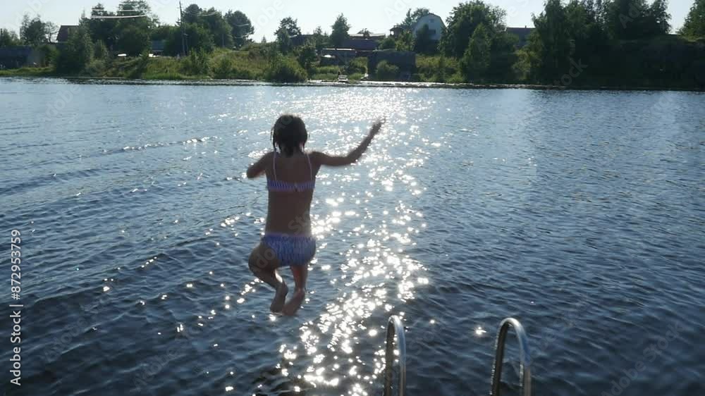Slow motion child jumping off dock. Girl jumping into the lake at summertime vacation. Slow motion child jumping off dock. Girl jumping into the lake at summertime vacation.