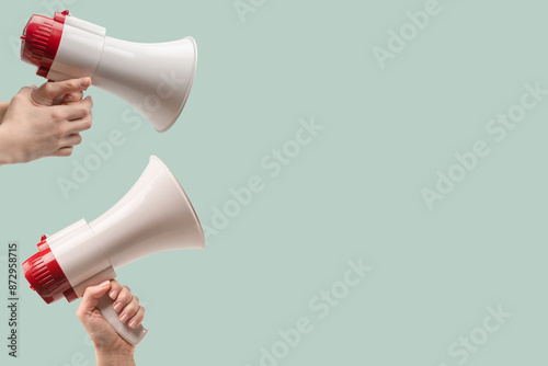 Megaphone in woman hands on a green background.