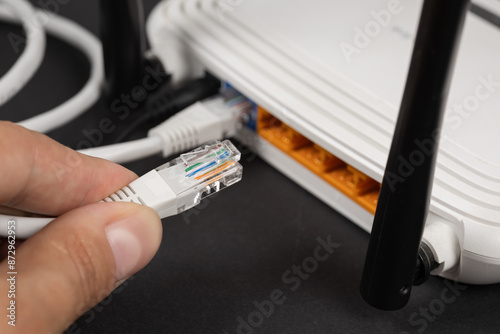 Fotografie Man plugging internet cable into wi-fi router