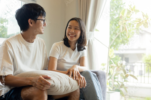 close up asian woman and man sitting together on couch and talking with each other with happiness emotion about family and relationship for mental health of couple lifestyle concept