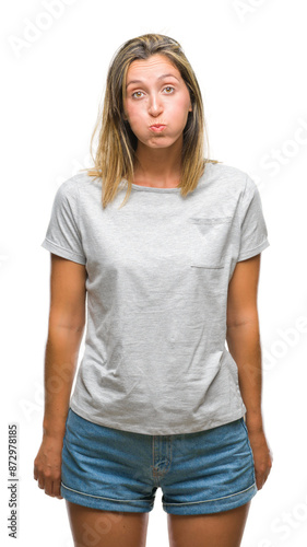 Young beautiful woman over isolated background puffing cheeks with funny face. Mouth inflated with air, crazy expression.